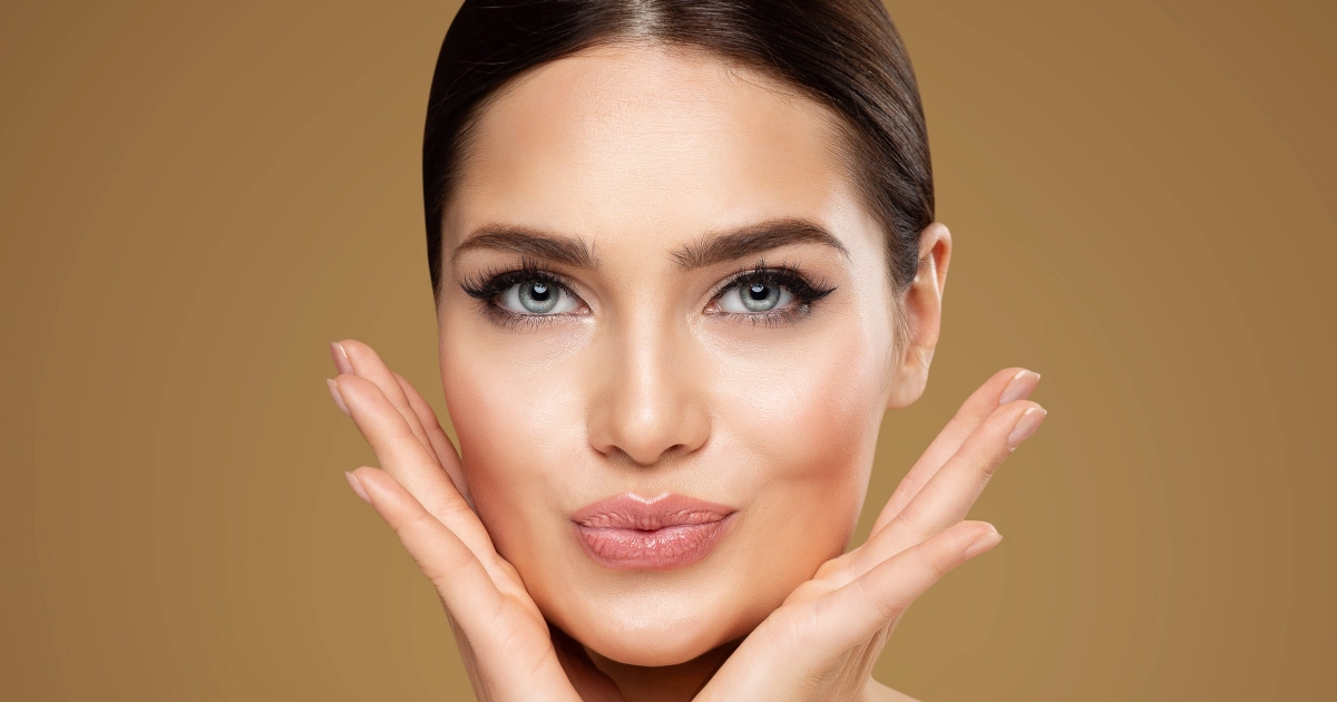 Woman with flawless skin showing her face gently touched by hands after Permanent Makeup session in Princeton, WV